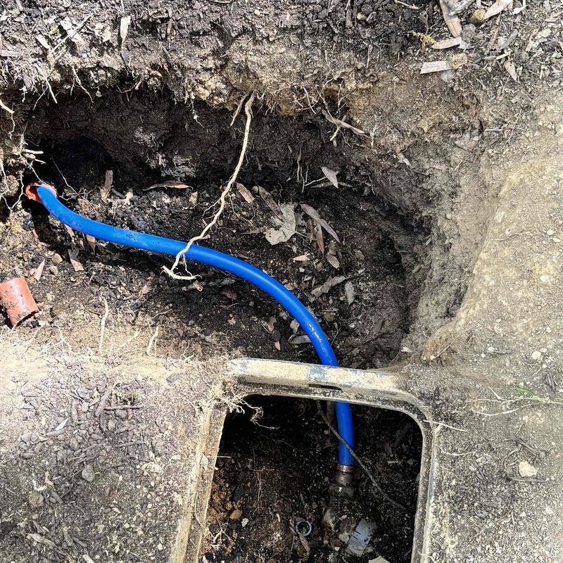 Blue underground water pipe installation near valve box