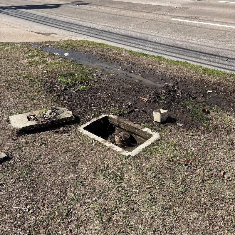 Storm drain with open manhole and mud runoff