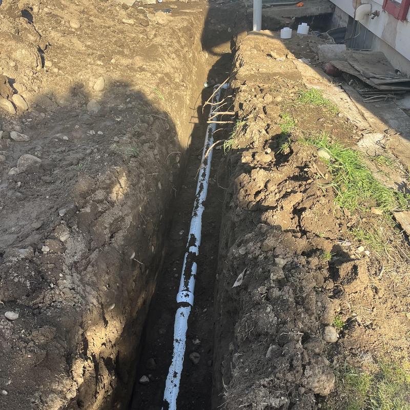 Sewerline installation in trench next to house foundation Sewerline installation in trench next to house foundation