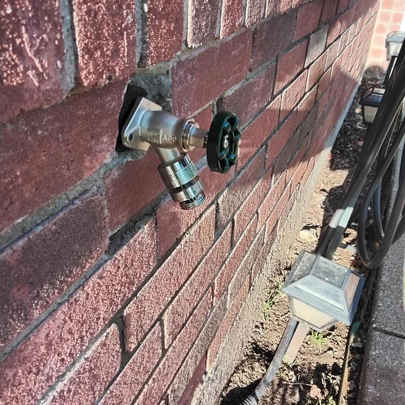 Exterior hose bib with vacuum breaker on brick wall