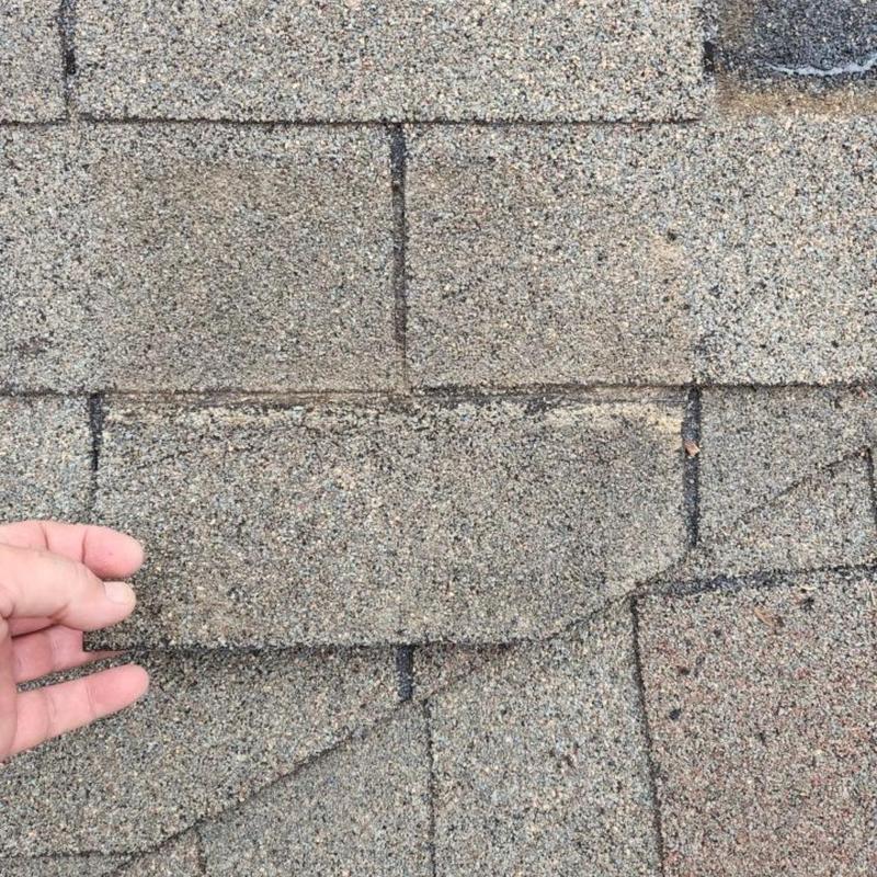 Storm damaged asphalt shingles being replaced by roofer