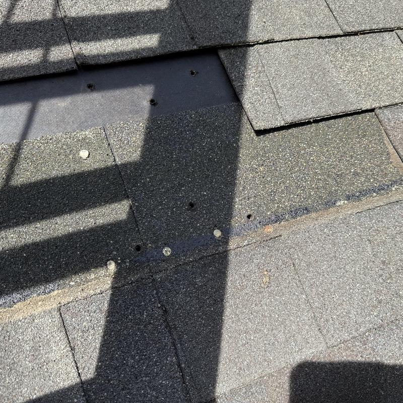 Roof shingles with exposed nail holes on repaired section