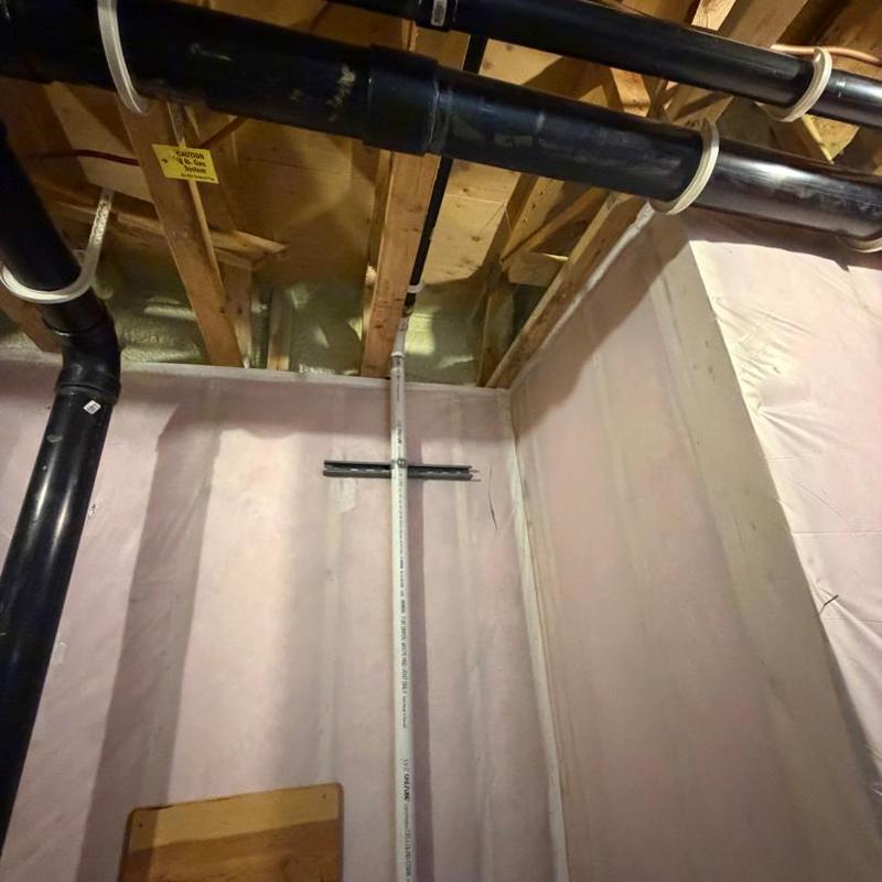 Sump pump discharge pipe installation in basement corner