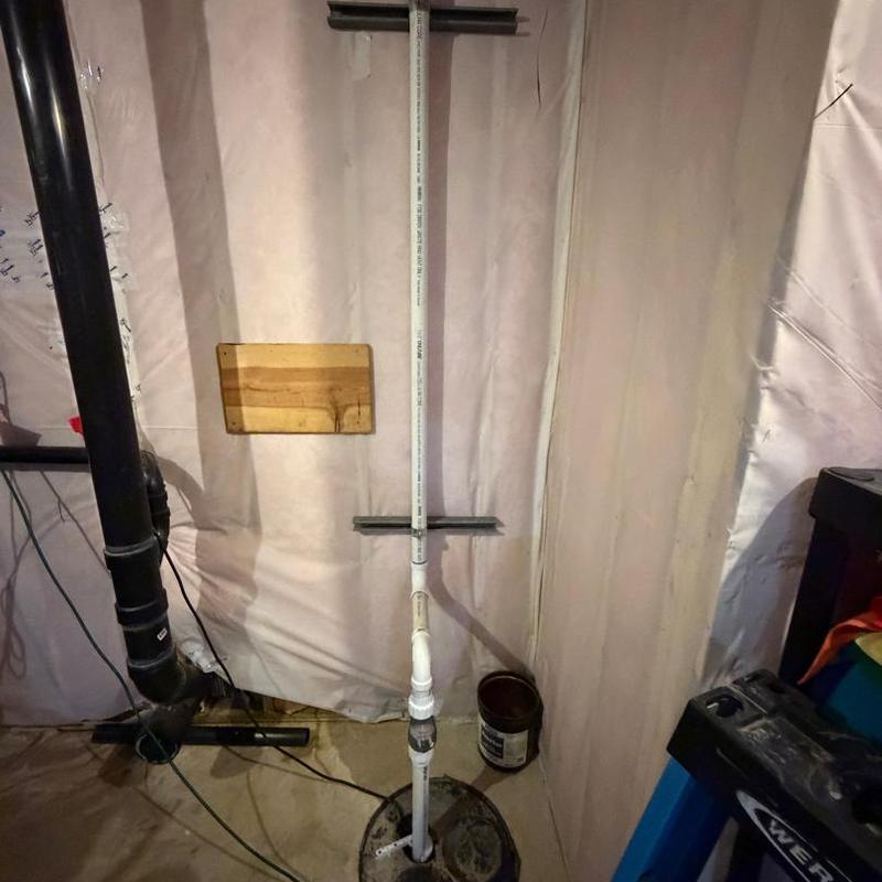 Sump pump discharge line in basement corner