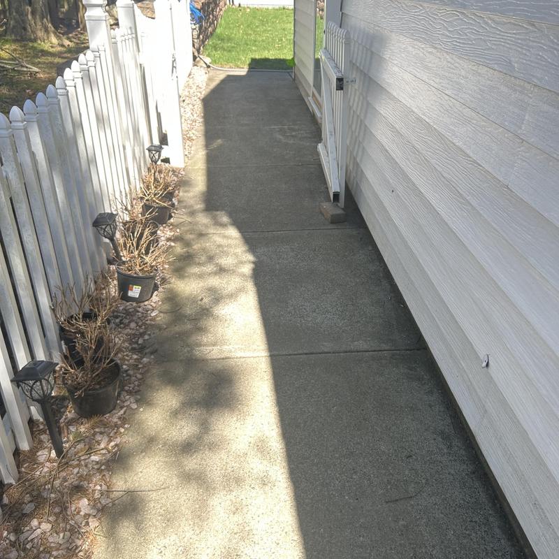 Concrete pathway next to white fence and house siding Concrete pathway next to white fence and house siding