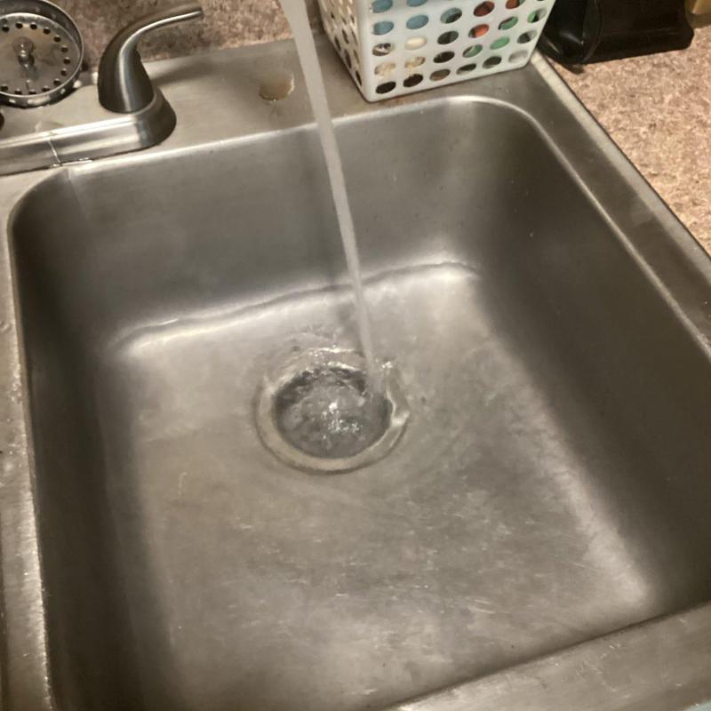 Kitchen sink drain with flowing water in stainless steel basin