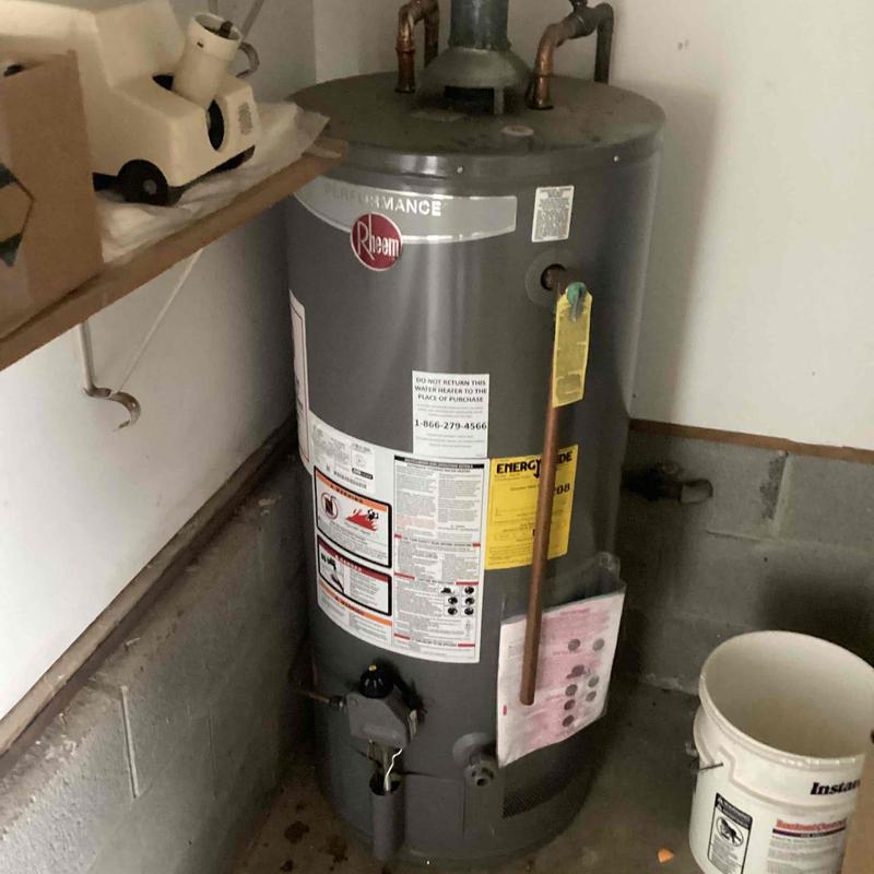 Water heater unit in basement corner with pipes