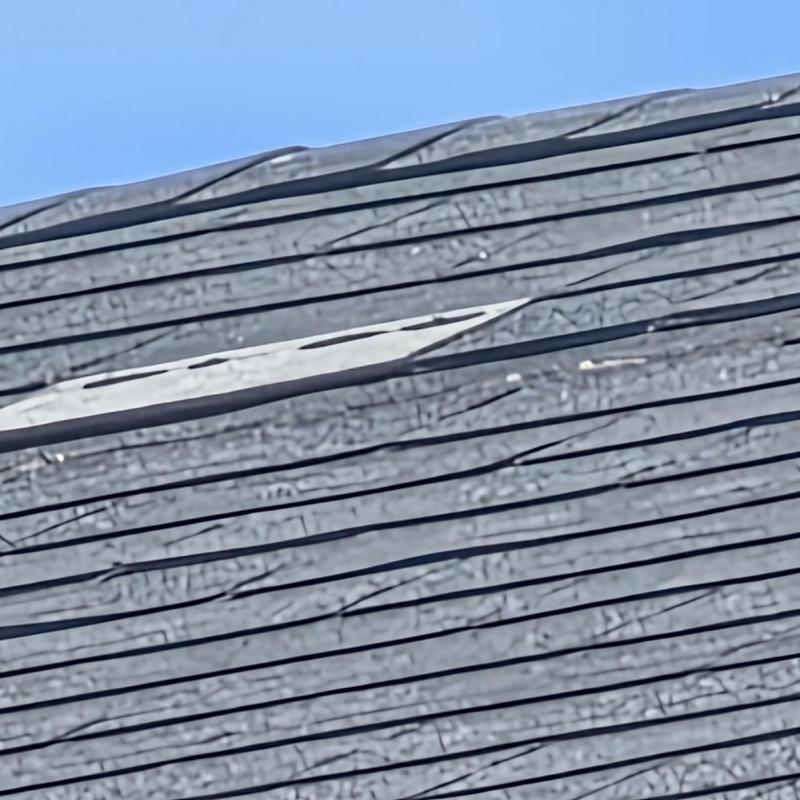 Asphalt roof shingles with wind damage and missing section