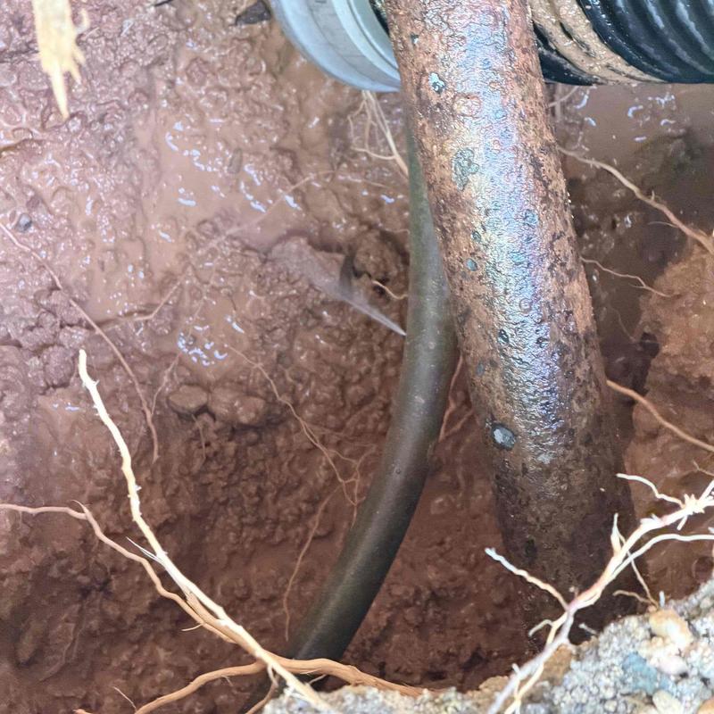 Leaking underground rusted metal pipe with water spray