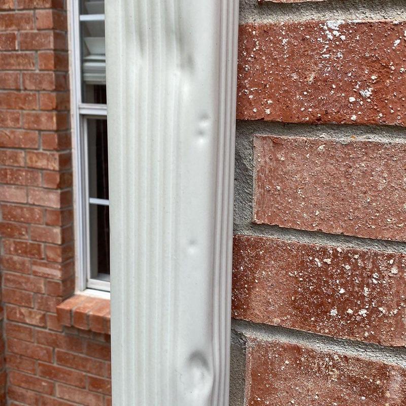 Metal gutter with hail storm dents on brick house exterior Metal gutter with hail storm dents on brick house exterior