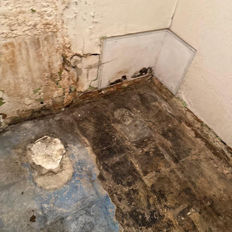 Concrete floor damage and wall mold in corner room