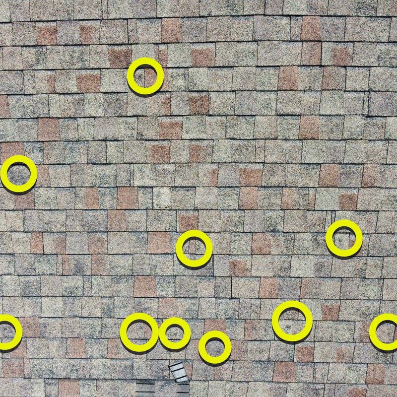 Roof shingles with hail damage marked in yellow circles