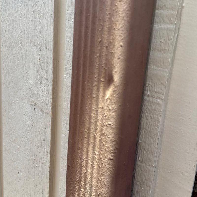 Metal downspout with hail damage dent and pitting