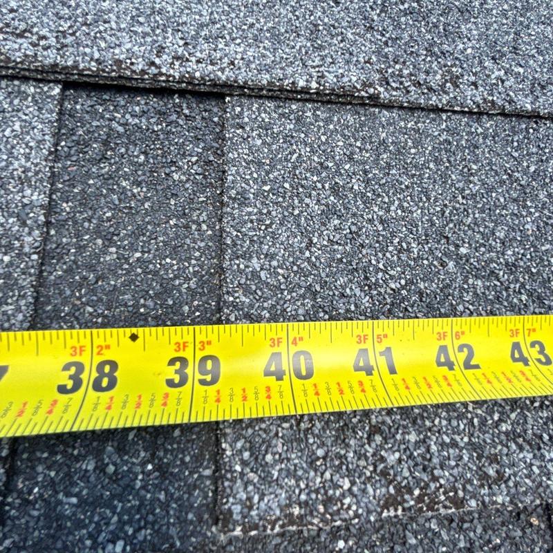 Asphalt shingles with tape measure showing damage