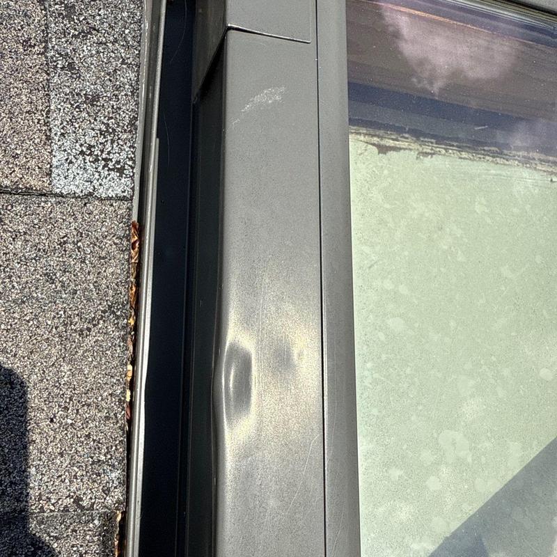Metal window frame with hail damage dents close-up