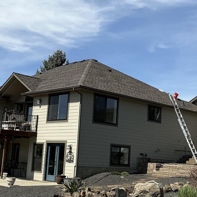 Asphalt shingle roof with ladder and repairs underway