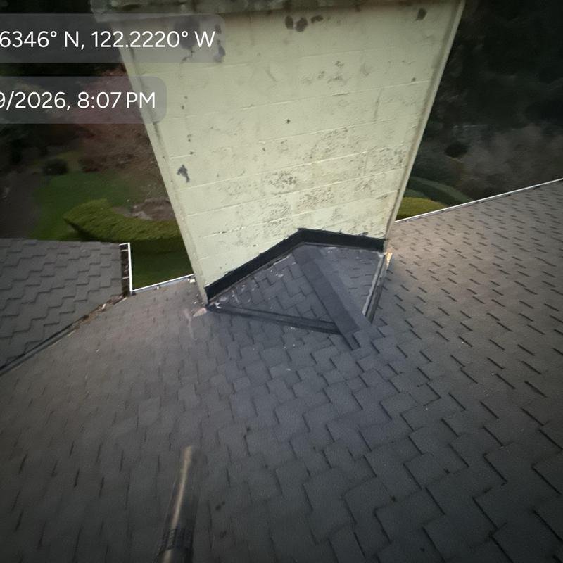 Chimney flashing with new shingles on roof slope