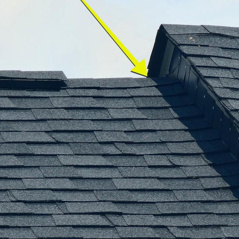 Roof shingles with yellow inspection arrow pointing defect