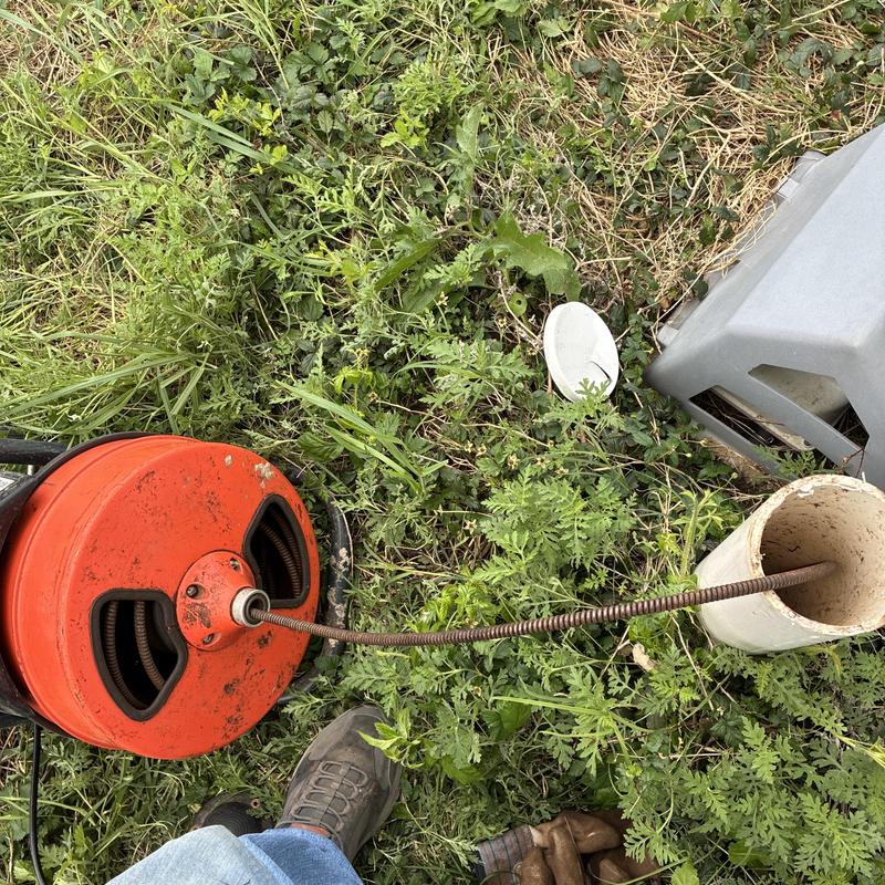 Sewer line drain cleaning machine with cable in grass