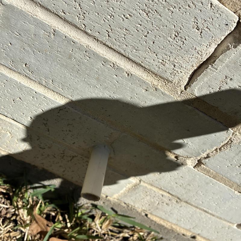 Pressure relief line entry on garage wall with sealant