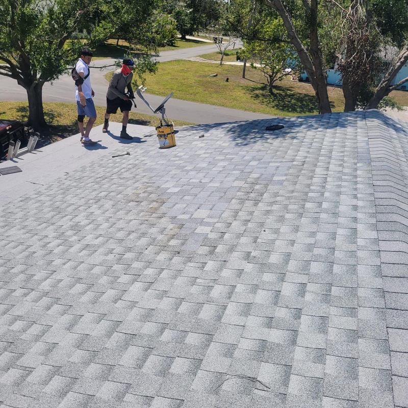 Shingle roof with repair crew inspecting damage