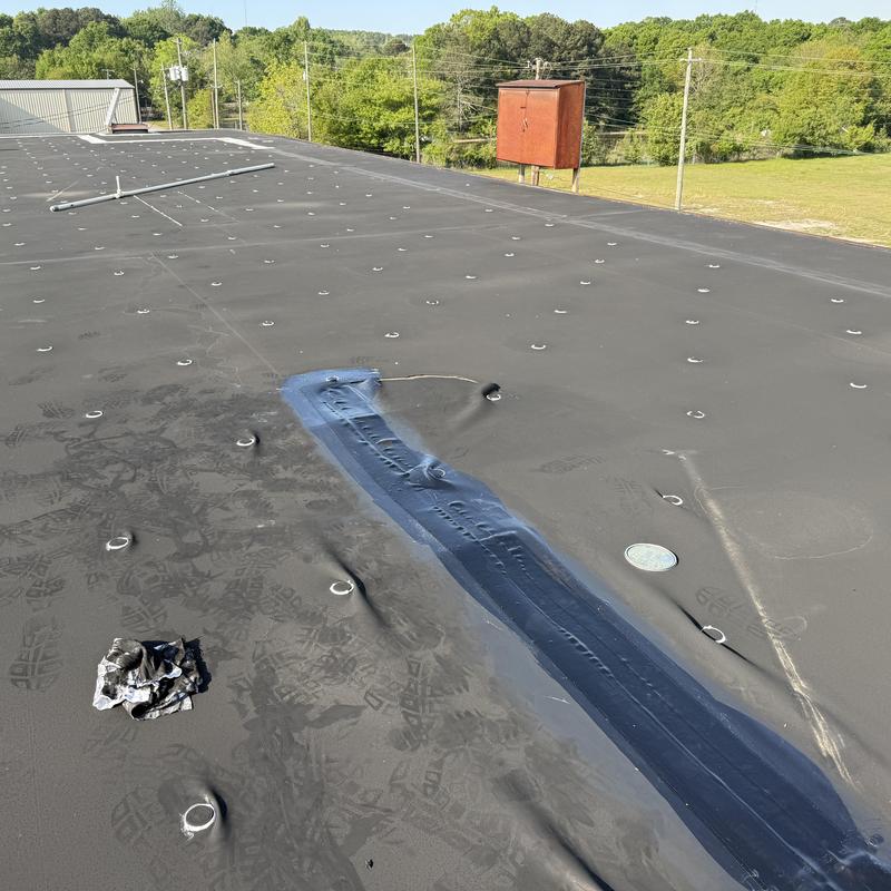 EPDM roof membrane with patched tear near AC unit