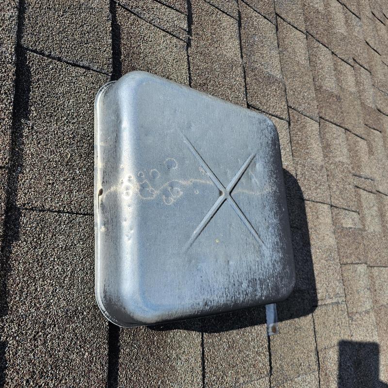 Metal roof vent with hail impact dents on shingles