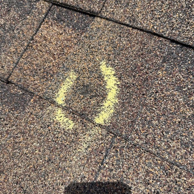 Asphalt shingles with yellow chalk marking damage