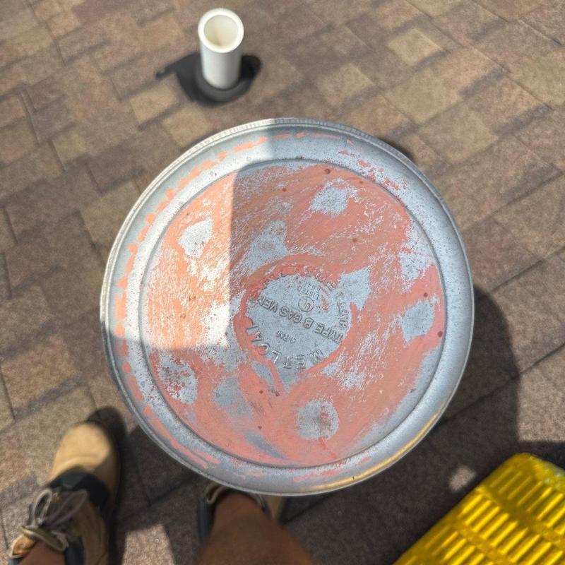 Metal roof vent with rust and shingle background