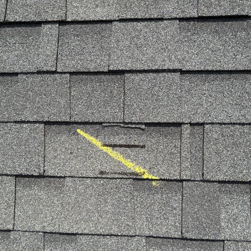 Asphalt shingle with hail damage marked by yellow chalk
