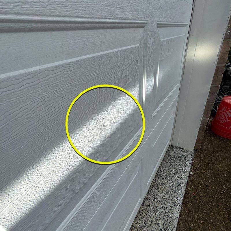 Garage door dent damage highlighted on white panel