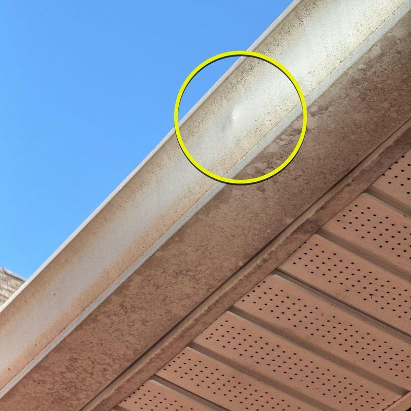 Metal gutter dent with minor hail damage circled in yellow