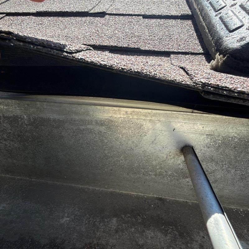 Roof shingles with hail damage near metal gutter edge