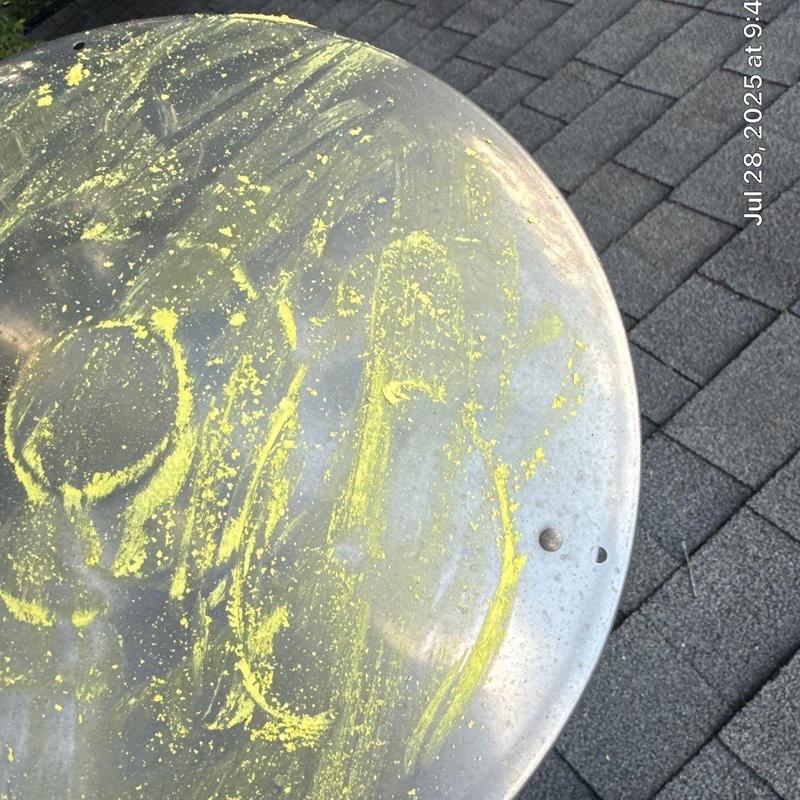 Satellite dish with yellow pollen on roof shingles