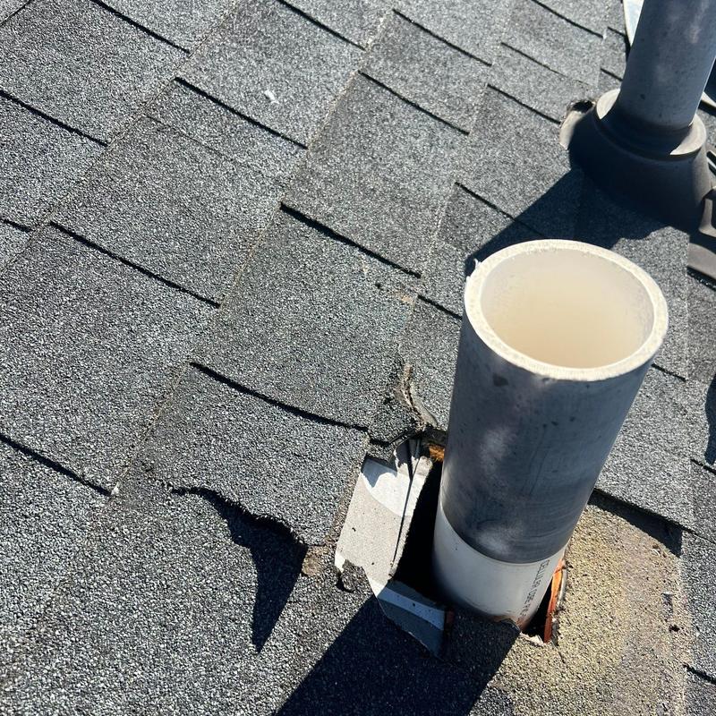 Roof shingles with damage near vent pipe on asphalt roof