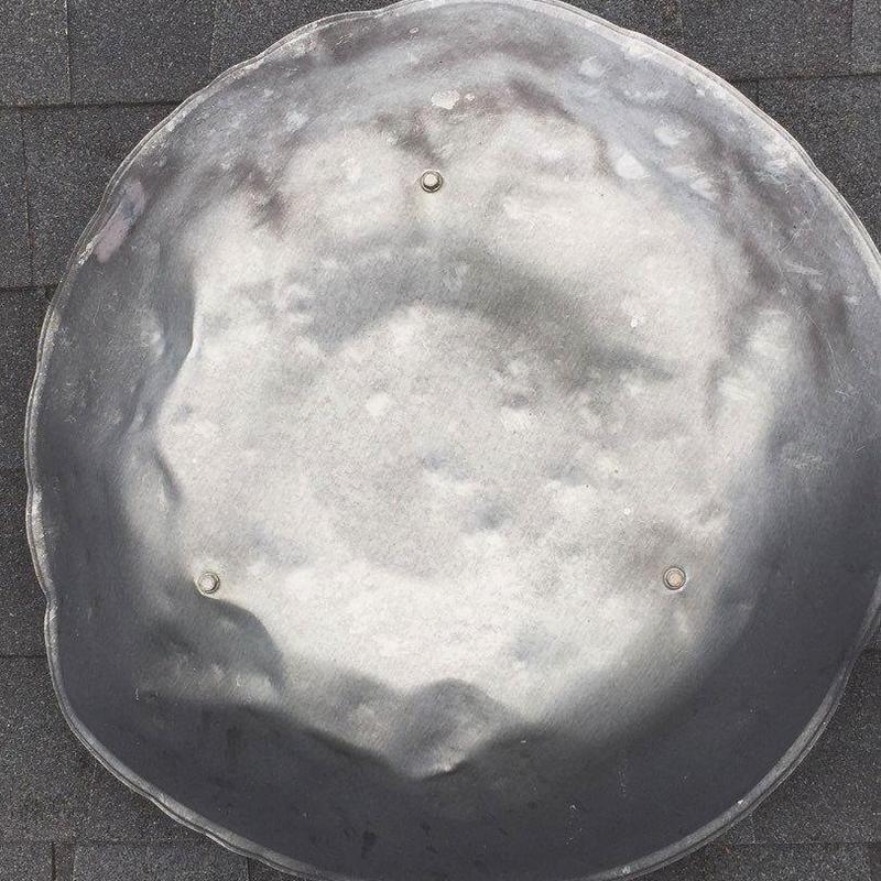 Metal roof vent with hail damage dents visible Metal roof vent with hail damage dents visible