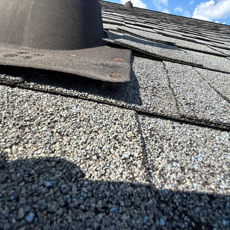 Asphalt roof shingles with hail damage near vent flashing