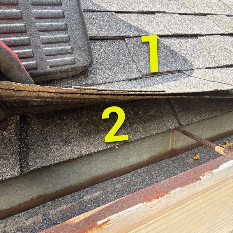 Asphalt roof shingles lifted showing hail damage and roof deck