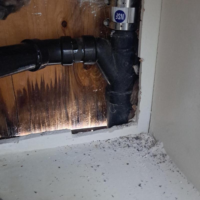 Drain pipe section inside wall with clamp and cut-out drywall