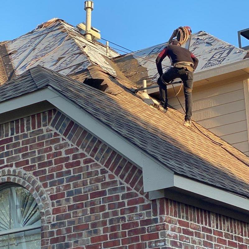 Asphalt shingle roof with worker repairing damage Asphalt shingle roof with worker repairing damage