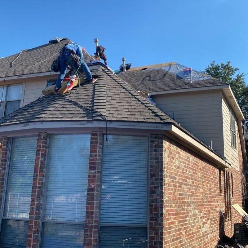 Asphalt shingle roof with workers inspecting and repairing Asphalt shingle roof with workers inspecting and repairing