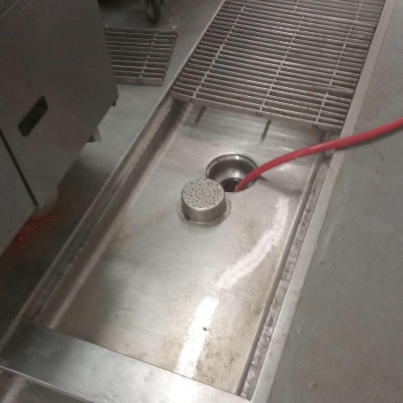 Main line drain with red hose in stainless steel tray