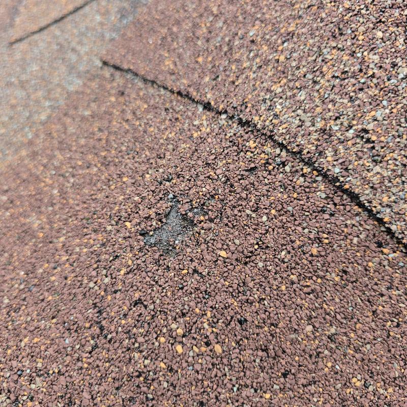 Asphalt shingle roof with hail impact damage close-up
