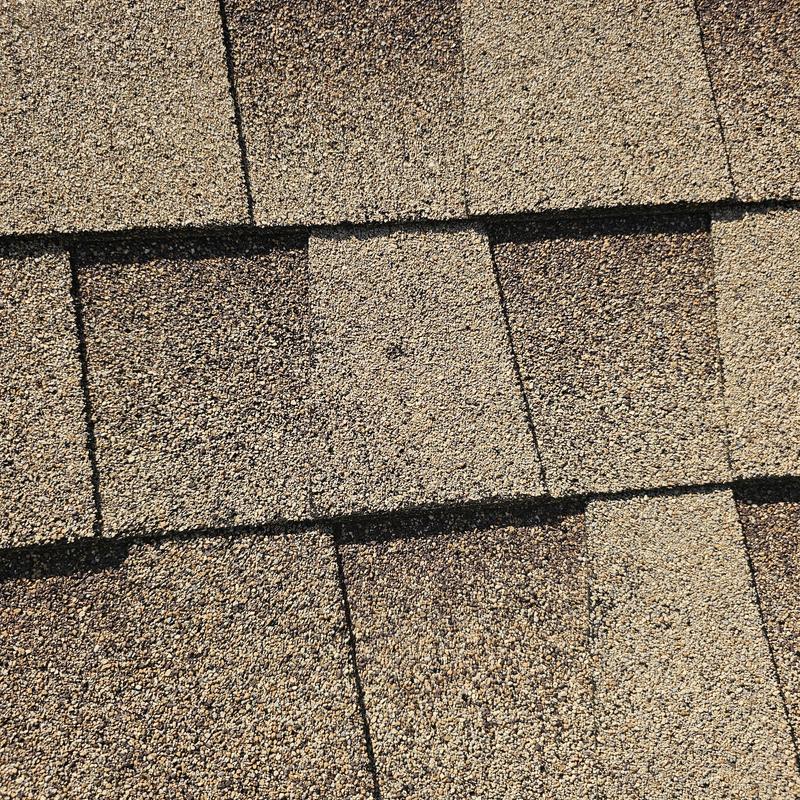 Asphalt roof shingles with hail and wind damage close-up