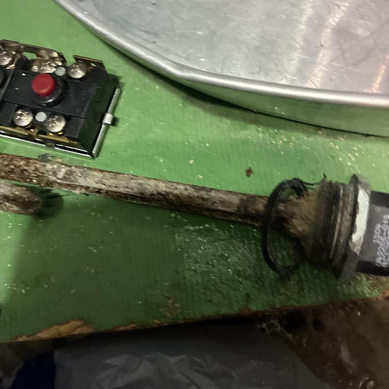 Water heater heating element and thermostat parts on green floor