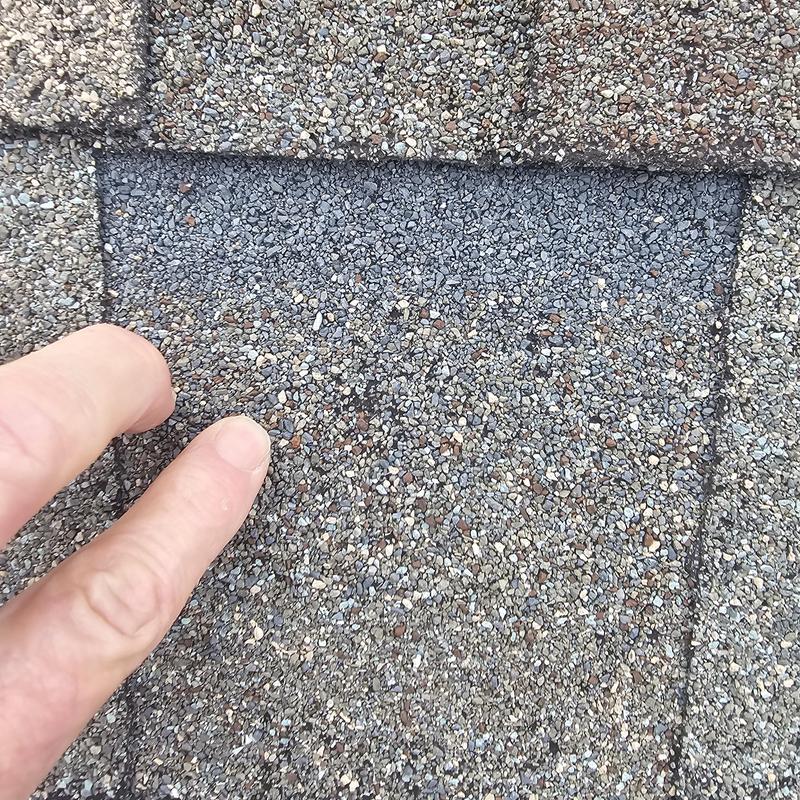 Asphalt roof shingle with hail damage close-up inspection