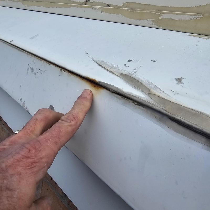 Metal drip edge with rust and hail damage signs