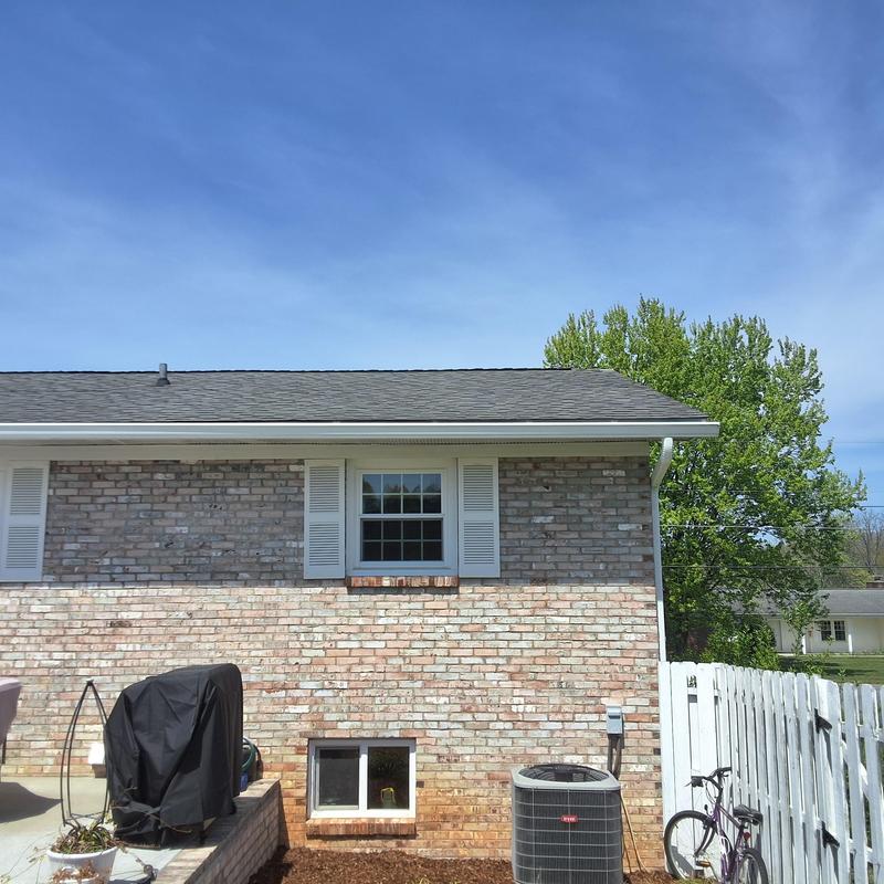 Asphalt shingle roof on brick home under clear sky
