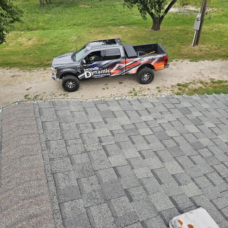 Asphalt shingle roof with hail damage and roofing truck