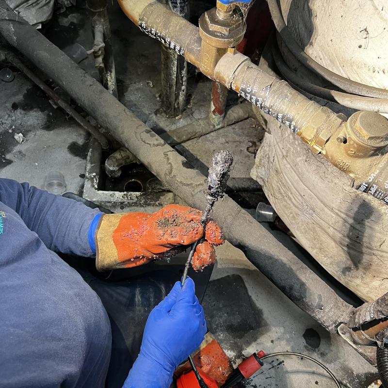 Floor sink drain snake removal with gloved hands Floor sink drain snake removal with gloved hands